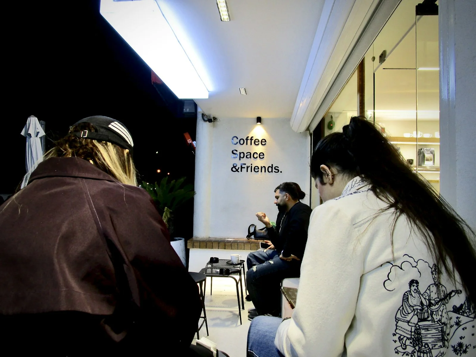 People gathered outside a coffee shop at night People gathered outside a coffee shop at night