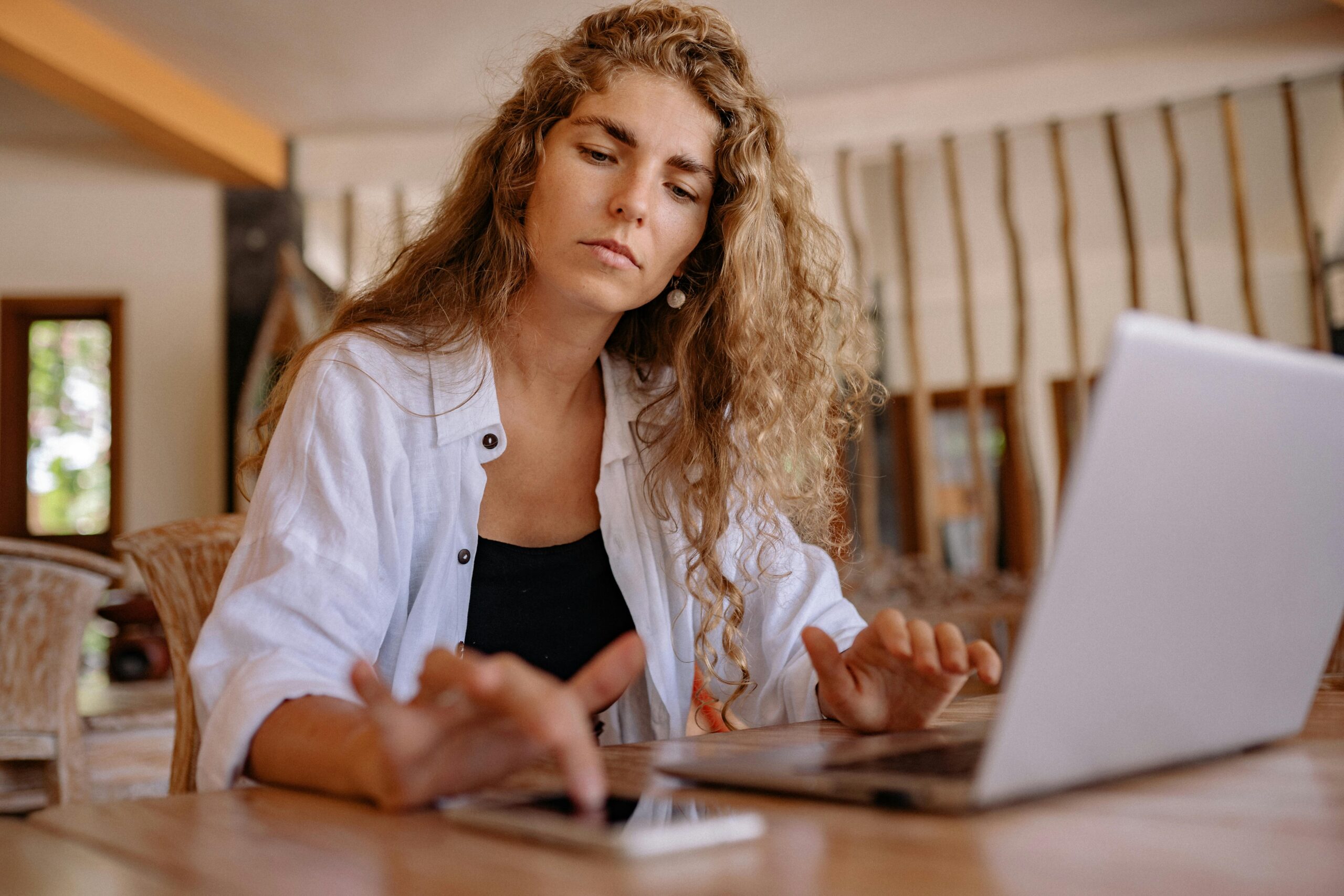 Using free directories A woman intently works on a laptop while using a smartphone indoors, symbolizing modern remote work.