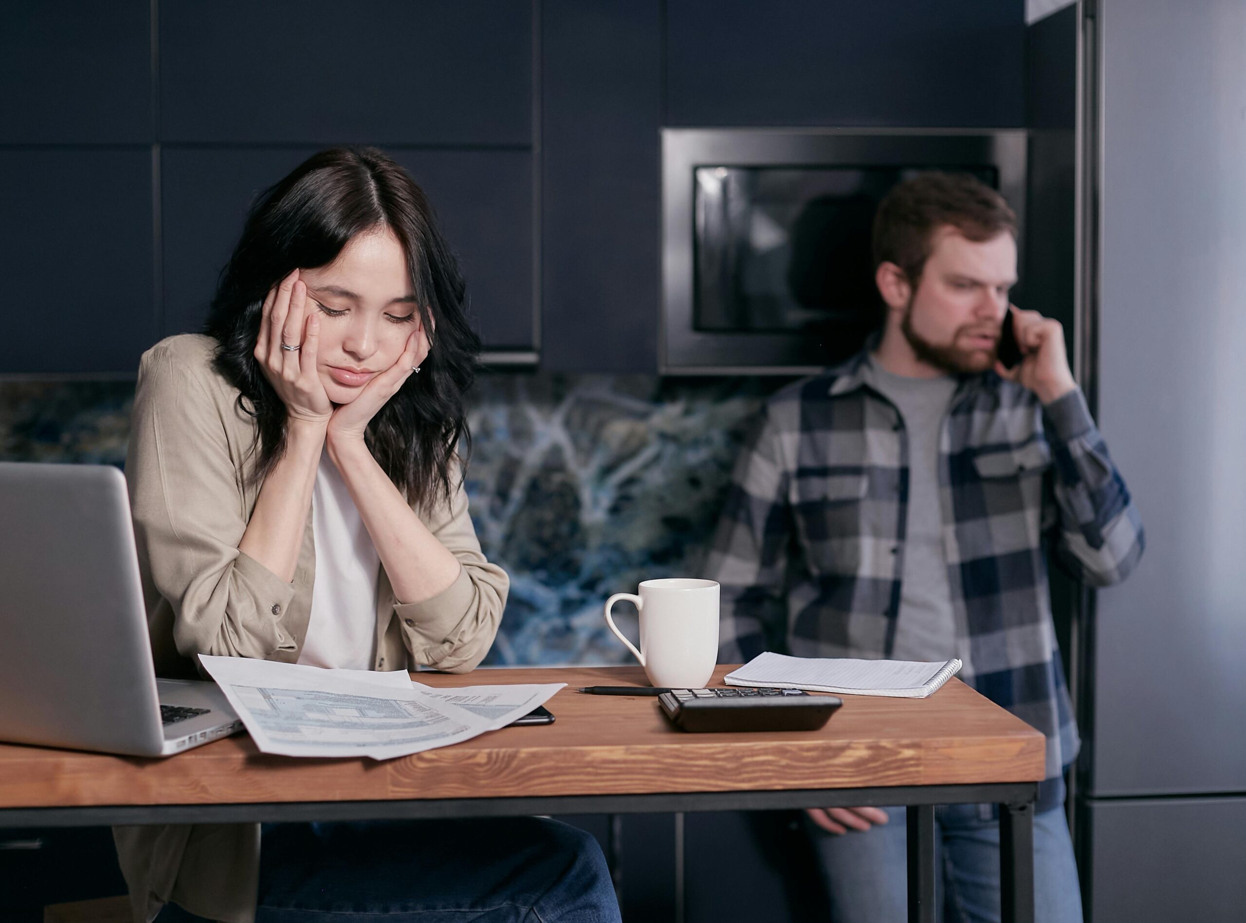 Invoices not getting delivered? A couple dealing with financial stress, surrounded by bills and a laptop indoors.